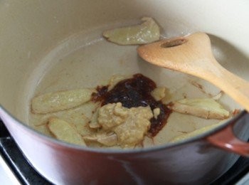 step2: 麻油辣豆腐乳加少許紹興酒攪拌成泥。白蘿蔔去皮切大塊，老薑切片，洋蔥切片。炒鍋加少許油小火加熱，放入薑片稍微煸香，放入半份豆腐乳與豆瓣醬炒香。倒入牛五花肉拌炒入味，加入洋蔥拌炒。