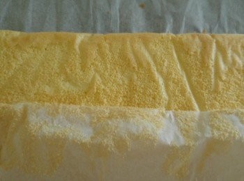 step5: 將淡忌廉加糖打成企身雪凍備用,芒果切粒備用。準備另一張牛油紙將蛋糕面倒扣在牛油紙上攤凍後撕去蛋糕的牛油紙。