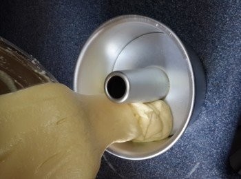 step11: 將榴槤麵糊往高处倒入戚風蛋糕模內。 用兩手約拇指輕按住柱狀內模， 其餘的手指則按住外模，拿起模型輕輕扣打， 讓麵糊均勻地平整開來
