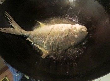 step3: 锅中烧热油，以慢火把鱼炸五至七分钟呈金黄，捞出备用。