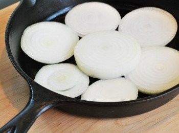 step5: 取一厚底鑄鐵鍋或深底烤盤，底層鋪上橫切甜洋蔥，皮朝上鋪上雞大腿（保留醃料）