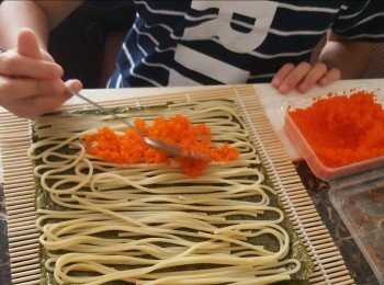 step7: 用同一方法將壽司紫菜鋪在壽司竹卷上，囡囡代勞將都好的意粉平均鋪在紫菜上，鋪入適量蟹籽於全部意粉上，用壽司竹卷卷起定型