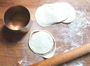 step11: 左手拇指及食指捏住麵糰邊緣轉圈(每個動作都必須撒粉,以免麵糰沾黏),同時右手用桿麵棍同時不停的桿麵皮(一邊轉麵皮,一邊桿麵),直徑約8cm中間厚邊緣薄的水餃皮。ps:如果做出的水餃皮不圓,可用圓型模具壓出圓形亦可。如圖示