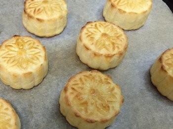 step12: 12.一小時後從雪柜取出月餅,放入焗爐內先焗五分鐘,取出,小心輕輕掃上一層旦液(切勿貪心掃太多,否則會令印花模糊及月餅塌下來),塗旦液後,讓其靜置十分鐘後再薄薄多塗一層旦液,放回焗爐中,再焗四分鐘,取出,再薄塗一層糖水,再焗一分鐘後可出爐了