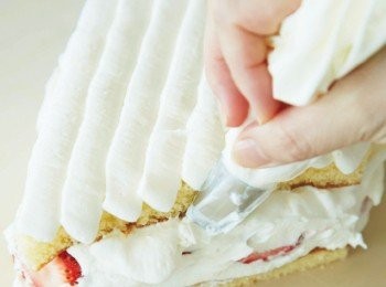 step16: 在海綿蛋糕表層也塗上糖漿，擠上發泡鮮奶油，並在側面擠上發泡鮮奶油蓋住草莓，再用抹刀抹平表面。放入冷凍庫直到蛋糕四周變硬為止。