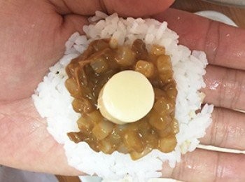 step3: 將白飯以四分之一的份量鋪平後、再將咖哩丁丁醬汁與起司球當做內餡，包成丸狀。