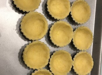 step6: 把撻皮團取出，看看自己的撻模多大？把粉團用木棒推成扁扁的長方形，用撻模印出所需嘅件數。
然後把印好皮放入撻模內，用手慢慢把推開。
每個撻皮上用叉拮孔，避免焗時撲起。