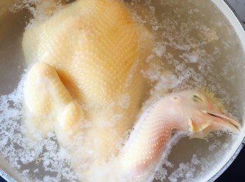 step4: 轉最小火，將整隻雞浸在水中，加蓋先煮6分鐘。開蓋後再將雞拿起讓血水流出，然後再加蓋煮6分鐘。