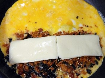 step2: 平底鑊下少少油燒熱。。。倒入蛋汁。。。稍稍凝固時。。。靠ㄧ邊放入紫菜豬肉鬆。。。上面再放芝士片!