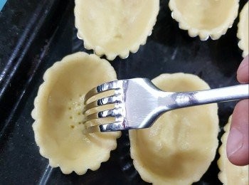 step8: 將已經磅好一粒粒的撻皮放入3寸長形撻模內，用手指由底部開始按平，再由邊位推上,貼模地向上推,再用义於皮的底部插洞(插洞作用是令皮底部焗時不會脹起