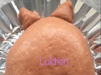 step2: 龍貓身的做法～ 取一份朱古力麵糰用手壓平成橢圓形後，在頂部切下大約兩份3g 的麵糰做成小耳朵。
餘下的麵糰用棍再壓平，中間放上所選用的<span class="group_3">餡料</span>，收口，揉壓成橢圓形放在焗盆上。
將兩個小耳朵用水貼在龍貓頭上的位置。蓋上保鮮紙發酵約30-45 分鐘。