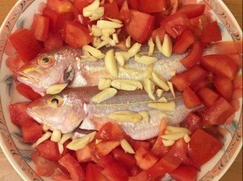 step2: 先放魚於碟置中，蕃茄圍邊放，魚身放蒜頭。