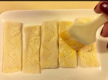 step2: 然後用一隻小义子於酥皮上插3-4下，讓酥皮焗起上來有少許空間，再用蛋漿於每一條長形狀的酥條塗上一層薄蛋漿，然後放入烤爐內烘烤7-10分鐘，直到酥皮金黃色。