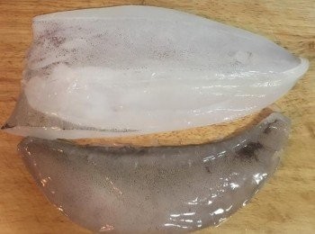 step2: 切下半邊的軟絲，手握廚房用紙巾（防滑）把它的肉鰭撕下；因為這隻軟絲夠新鮮，所以身上的皮也不用撕，如果買的是冷凍後解凍的，則可以用撕肉鰭的方法把皮撕下來。