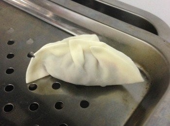 step3: 用筷子㧕一勺饀方在餃子皮中央，皮的邊沿沾蛋白液後並對摺揑實摺花