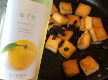 step4: 焗好的麵包、提子乾加入柚子蜜糖拌匀。最後刨些檸檬皮及橙皮，均勻灑在表面即可。