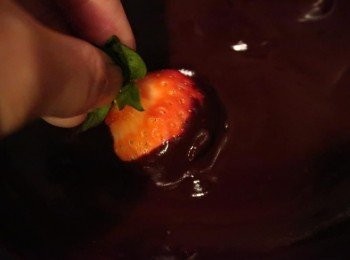 step3: 將洗淨的草莓裹上巧克力並抖掉多餘的巧克力，沾的同時，頂部可以留白，讓部分草莓的色澤顯露於外，更有層次。 （若天氣太冷，巧克力凝固太快，巧克力底部可以墊碗熱水）