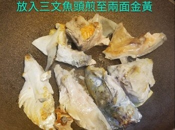 step1: 熱鑊下油放入3塊薑片爆至微微金黃，放入三文魚頭煎至兩面金黃，棄掉薑片