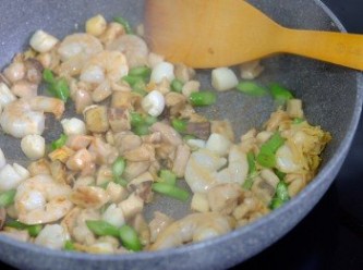 step3: 同一個鍋子，下少許油燒熱，加入雞腿肉炒香，加入蝦仁和帶子粒炒至半熟，加入冬菇、瑤柱絲和芥蘭粒同炒。