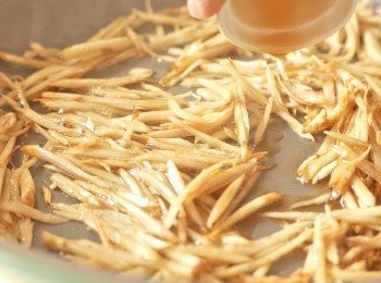 step4: 在鍋中加適量麻油，以中小火燒熱。隔除牛蒡的水份，以毛巾或廚紙印乾後，下牛蒡到鍋中炒5分鐘後，多加1湯匙麻油，以半煎炸的形式多煮5分鐘，間中拌炒。