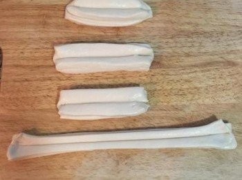 step17: 輕輕抓住兩頭的中間，食指和中指扶在油條中間的下方，慢慢地滑拉長成兩倍長。
註：如到這個步驟，油條麵糰還不夠柔軟，則寧願再蓋起來放讓麵糰繼續鬆弛喔～否則炸起來的成功率就不太一定。