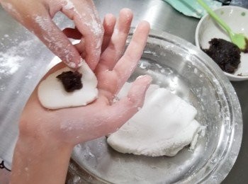 step2: 攞起少許白色麵團放在手掌中壓平，加入紅豆餡 ,搓成圓波波