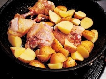step9: 棒腿肉上色到一定程度後，將馬鈴薯倒入。搖動平底鍋，讓材料裹滿油來煎煮。(把雞肉的美味湯汁也分享給馬鈴薯。放入1整顆帶皮的大蒜會更好！)