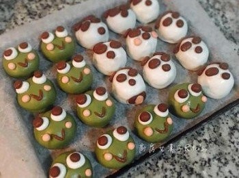 step13: 大的當眼球，沾點水後壓兩顆大的壓黏在白眼球上；小的則搓成條對折，沾水後壓在腮紅之間，大眼蛙芝麻湯圓完成。完全後蓋上保鮮膜放入冷凍庫冷凍，待變硬後即可移入保鮮盒，冷凍保存。
