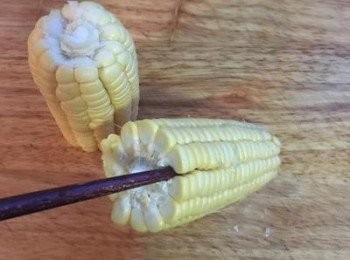 step2: 將玉米切成兩段，準備一枝木筷子，從上端往一排玉米的中間插入，往下插到底後，握住筷子上端往下扳，這一排的玉米就會掉下來。