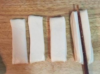 step16: 2片重疊後，在筷子上抹油，放在麵皮中間，輕輕往下壓，讓油條的中間能沾黏在一起，如果兩片沒法沾黏的話，可以用筷子點水在下方的麵皮中間，再疊上另一塊麵皮後再壓。