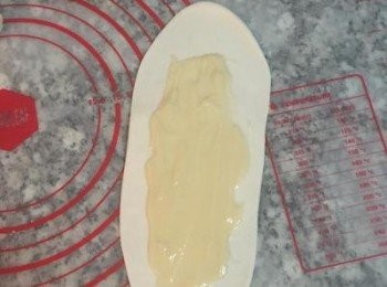 step10: 從第一顆揉圓的麵糰開始桿，用桿麵棍將麵糰桿成牛舌狀，並用湯匙在中間抹上油酥，四週都要留空間不要抹到，尾端那頭要特別留多一點，方便等一下的黏合。