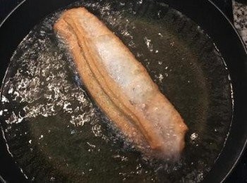 step20: 油條一下子就會蓬起變色。炸到上色後，直直地夾起，滴一下油後放在鋪了吸油紙的網架上，完成。起鍋時會是偏硬，起鍋後就會有點變軟，但外皮咬下去是鬆酥口感，跟外面賣的很像喔。