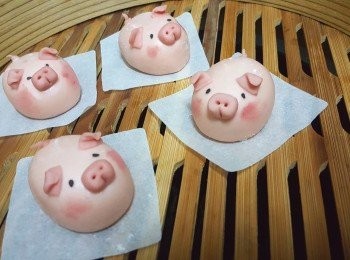 step2: 取適量淡粉紅色麵團搓成長橢圓形，壓平切半，做豬仔耳朵，再將豬耳朵向前彎；再取適量淡粉紅色麵團，做豬鼻子，用兩支牙籤平均整出鼻孔，再用牙籤在由下向上在兩個鼻孔中間壓出嘴巴；掃少許紅麴粉在豬仔臉上做腮紅