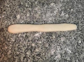 step9: 工作檯撒ㄧ點粉，將其中ㄧ條麵糰，用手略壓扁；（另一條請用保鮮膜包起來備用）