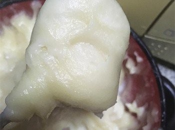 step3: 在案板上鋪一層保鮮膜，將稍冷的糯米麵團分成兩份，另鋪一個保鮮膜在案板上，然後把一份麵團放上去，再在麵團上鋪一層保鮮膜，用擀麵杖把麵團擀成長方形。另一份麵團也一樣。