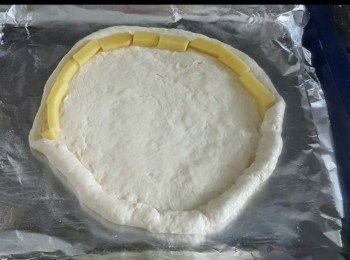 step4: 先將錫箔紙鋪上焗盤， 再抹點油， 然後把已鬆弛的麵團放上去，桿成大圓形。

麵皮外圍放上起mozzarella 芝士條 （買整塊的mozzarella 芝士，切成條狀再來包), 再將芝士包入邊緣, 接口要壓一下, 讓麵皮黏合。