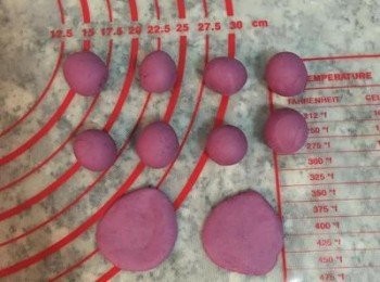 step20: 將紫薯麵糰排氣後揉成長條；
取50g紫薯麵糰，分割成10顆，每顆5g重的麵糰；揉圓後壓扁，用手指沾濕一面，黏在刈包中間略偏下的位置。