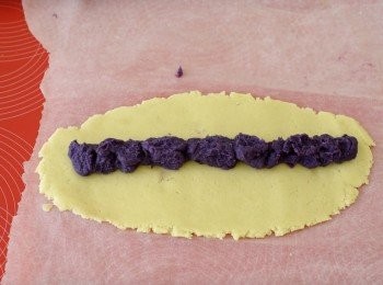 step3: 將麵糰分成5份，放在烘焙紙上，再在上面鋪一張烘焙紙，然後擀成長形薄片(約1cm厚）在中間放上紫薯蓉，然後捲起