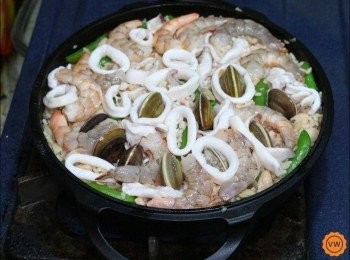 step12: 再將米飯抹平後鋪上蝦肉，上蓋稍加燜煮至湯汁微微收乾時，開蓋再放入已事先燙熟的透抽，最後再放入蛤蜊，加蓋燜至湯汁收乾。