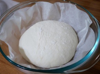 step6: 然後準備張烘焙紙，麵糰折疊縮口面朝下，將整形好麵糰移至烘焙紙上，
用夠大也可阻絕空氣的容器倒扣於麵糰上，做二次發酵。
(歐巴桑使用大容量玻璃攪拌盆做覆蓋，方便觀察麵糰變化狀況)
如配方再分糰，則連著烘焙紙移入適合器皿中，
覆蓋好阻絕空氣，放冷藏要烘烤時再取出。