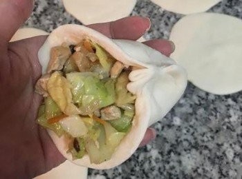 step15: 包法其實自己喜歡最重要。再左右拉摺到中間後捏緊，托著麵皮的手，大姆指配合著將餡料往包子裡塞，