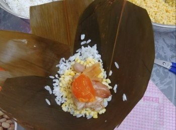 step5: 先放小許糯米，再放綠豆，中間加入蛋黃，豬肉，花生瑤柱。再放綠豆，最後放糯米，再摺合棕葉包好，用棉繩扎好。