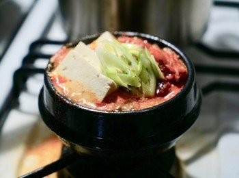 step3: 在鍋子裏豬腩片上，加入泡菜再加上豆腐，中間加入<span class="group_2">泡菜鍋醬</span>汁，最後加上湯，繼續以中火煮滾，若上湯不夠的話，可以加一點水