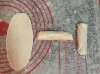 step11: 取第一個包好的,用橄麵棍從中間輕壓後分別向上及向下桿開桿薄,桿成牛舌狀；輕推捲起，依續排好。