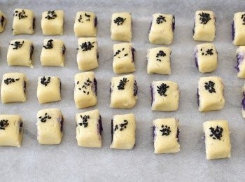 step4: 在中間放上紫薯泥，然後卷起. 再切成小塊，放在鋪有烘焙紙的烤盤上，塗一層蛋液，用手指沾點蛋液，然後沾黑芝麻，再沾在一口酥上作裝飾(*這步驟可省略）