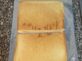 step17: 此時蛋糕已降溫，桌上鋪一張鋁箔紙亮面朝上；將蛋糕倒放在鋁箔紙上，撕去烘焙紙；並將ㄧ片蛋糕一分為二；