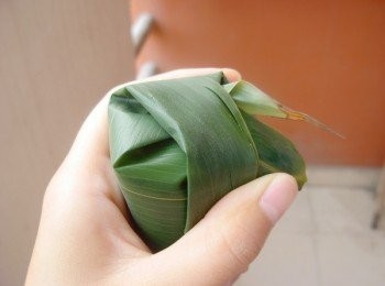 step4: 上面的粽葉往下拉，蓋住口，把兩邊的粽葉往里折，這樣既好看又不漏米，然後就用草繩自由綁，能包得緊，不漏米就可以了