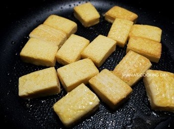 step4: 要先把一面煎的變色後再翻面喔，用鍋鏟把豆腐推到鍋邊後，輕輕用筷子往內撥就可以完成翻面了，外表要煎得完整等等在翻炒的時候才不會容易破碎。