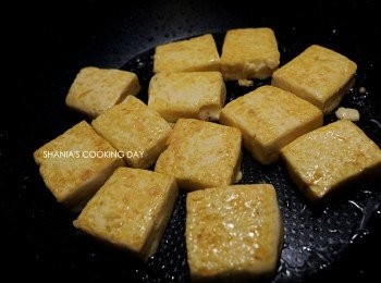 step3: 放入雞蛋豆腐，並將豆腐的兩面都煎至金黃後取出備用。
煎的成型一些，之後跟蛋黃蛋白一起翻炒的時候也不會容易碎裂。
翻豆腐的方法就是用鍋鏟將豆腐推至鍋邊，再用筷子往內撥就可以翻面成功囉。