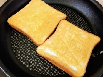 step3: 燒熱平底鑊，轉中火，將兩片麵包塗滿牛油的一面放於鑊上，煎至焦黃色。